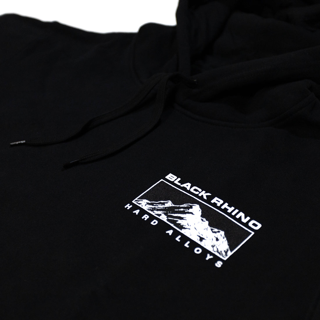 Black Rhino TRACER Hoodie in black, featuring a sleek design with a front pocket and hood, displayed on a wooden surface.