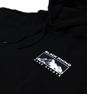 Black Rhino TRACER Hoodie in black, featuring a sleek design with a front pocket and hood, displayed on a wooden surface.