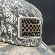 Hoonigan SPRINT unstructured snapback hat featuring a camo pattern and embroidered logo patch. Ideal for motorsport fans.