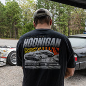 Man wearing a black Hoonigan SLIDEWAYS short sleeve T-shirt featuring a graphic of racing cars on the back.