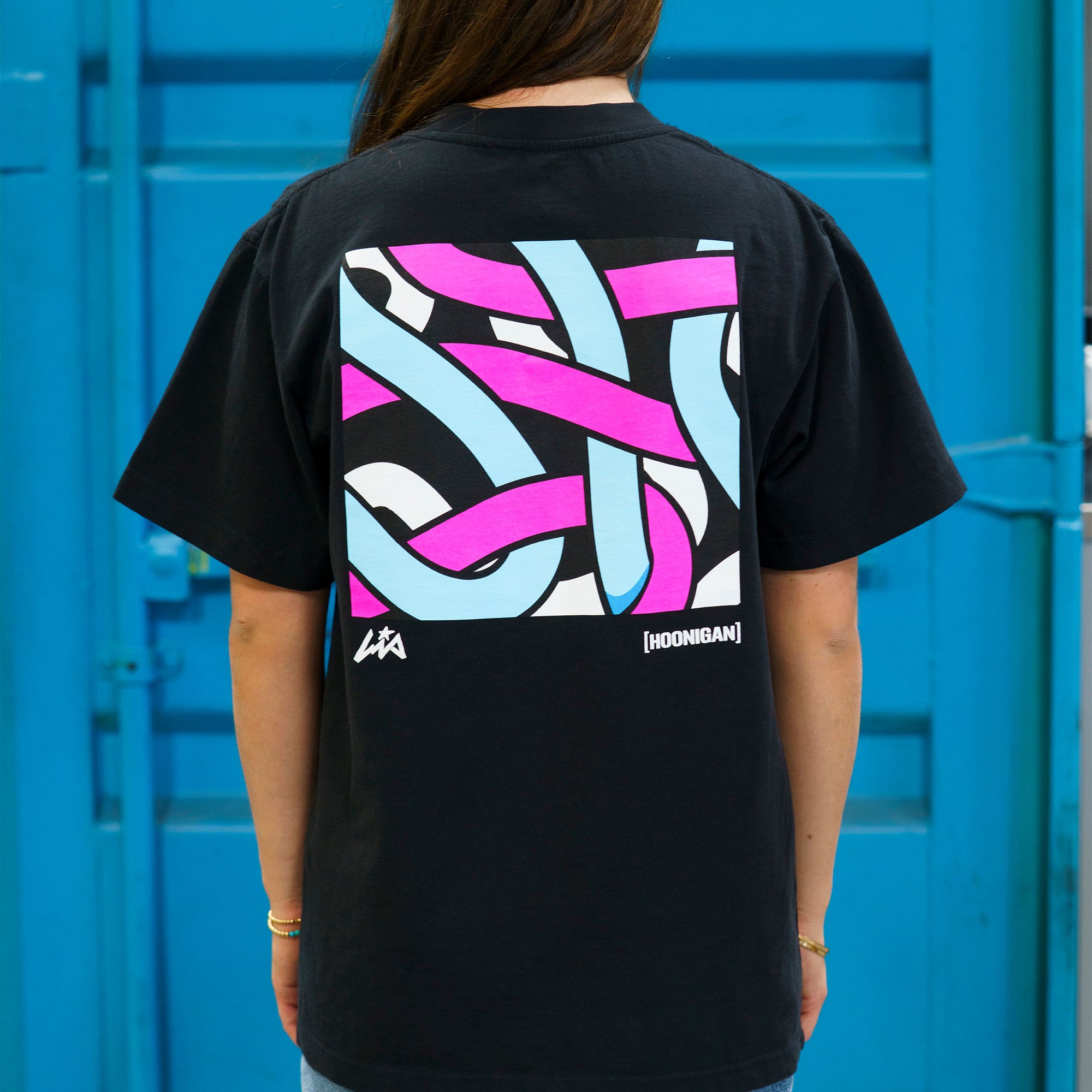 Black short sleeve tee featuring a colorful abstract design on the back, celebrating Hoonigan and Lia Block's collaboration.