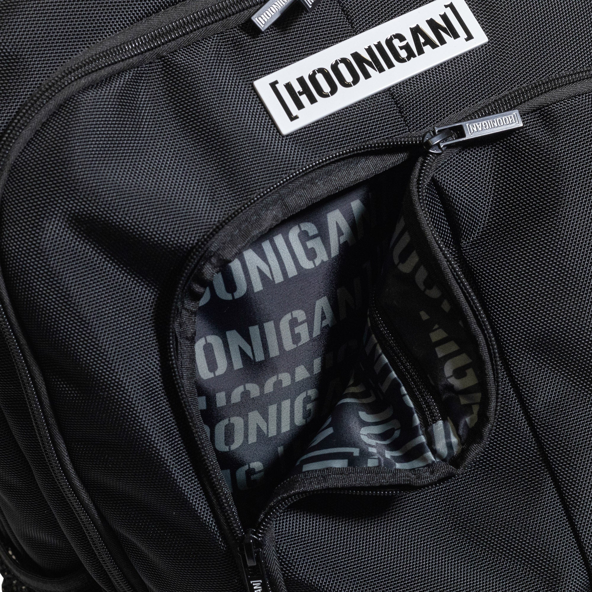 Hoonigan METAL BAR Backpack featuring a black exterior with a bold logo and adjustable straps.
