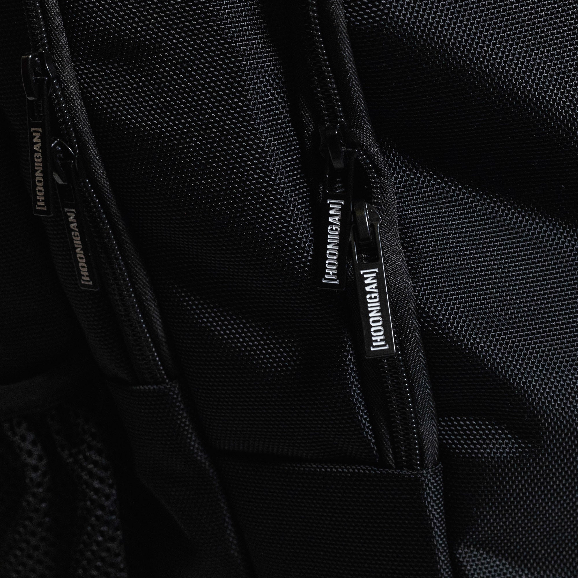 Hoonigan METAL BAR Backpack featuring a sleek black design with bold white logo and adjustable straps, perfect for casual outings and sports activities.