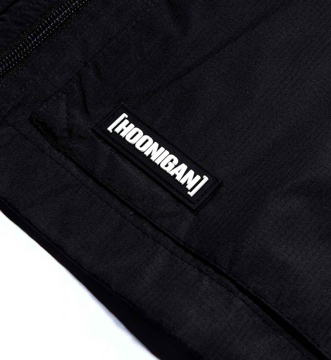 Hoonigan Standard Issue Windbreaker Jacket in black and white, featuring a front pocket and logo detail.