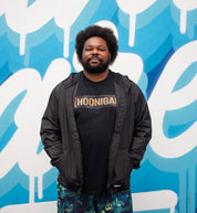 Hoonigan STANDARD ISSUE windbreaker jacket in black and white with logo detail, displayed against an outdoor backdrop.