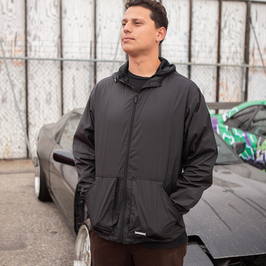 Hoonigan STANDARD ISSUE Windbreaker Jacket in black and white, showcasing a front view with logo detailing and a stylish, casual design.