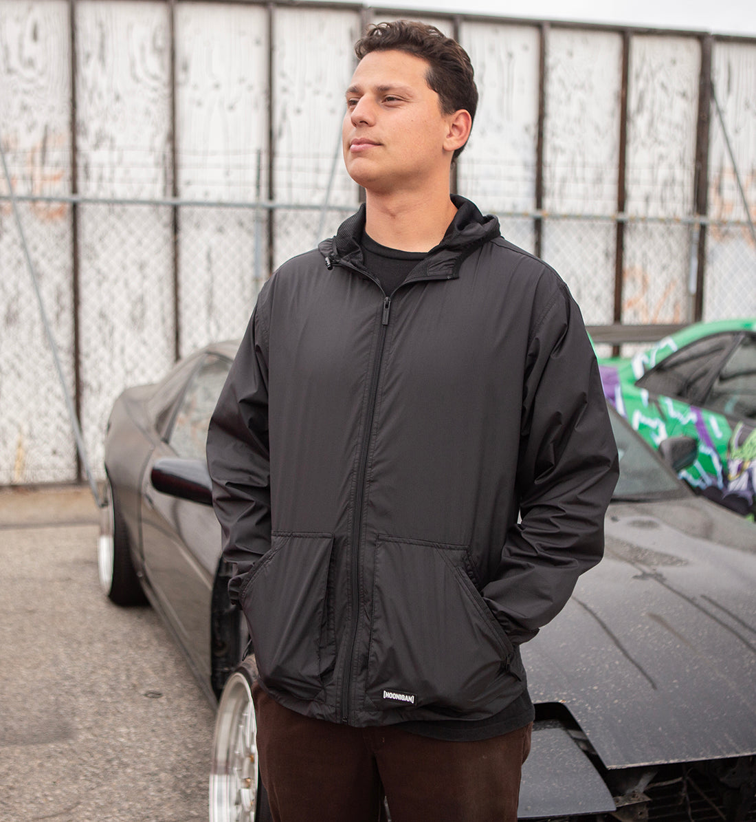 Hoonigan STANDARD ISSUE Windbreaker Jacket in black and white, showcasing a front view with logo detailing and a stylish, casual design.