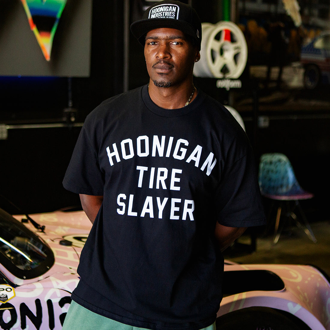 Black Hoonigan TIRE SLAYER short sleeve t-shirt displayed in a lifestyle setting, featuring a large front graphic of the "TIRE SLAYER" logo.