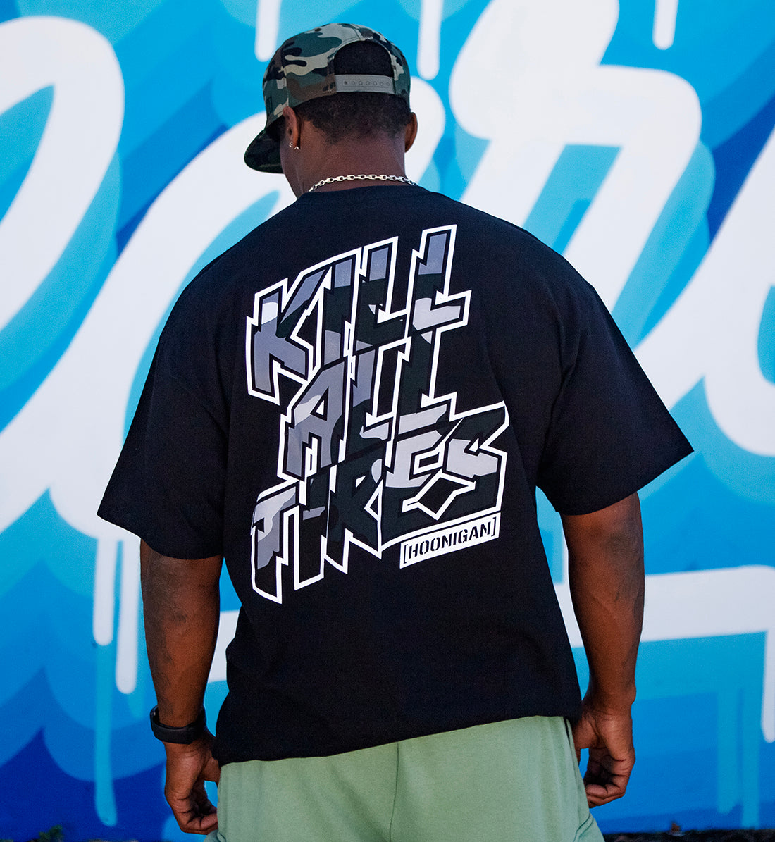 Hoonigan KILL ALL TIRES CAMO short sleeve tee in black with camo graphic, displayed in a lifestyle setting, showcasing its casual fit and stylish design.