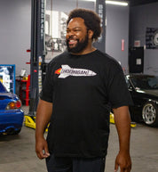 Hoonigan ROCKET Short Sleeve Tee featuring a vibrant graphic design on a black background, model wearing the shirt outdoors.