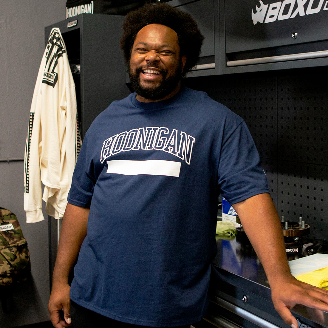 Hoonigan UNATHLETIC Short Sleeve Tee in navy blue, featuring a bold graphic design on the front, worn by a model in a casual setting.