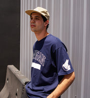Hoonigan UNATHLETIC short sleeve navy tee displayed on a model, featuring the bold "UNATHLETIC" graphic on the front.