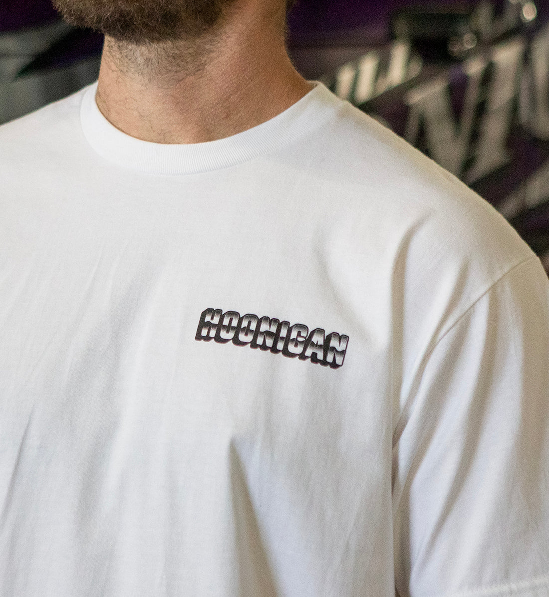 Hoonigan USED CARS Short Sleeve Tee in white, featuring a bold graphic design on the front, displayed in a lifestyle setting.