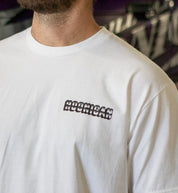 Hoonigan USED CARS Short Sleeve Tee in white, featuring a bold graphic design on the front, displayed in a lifestyle setting.