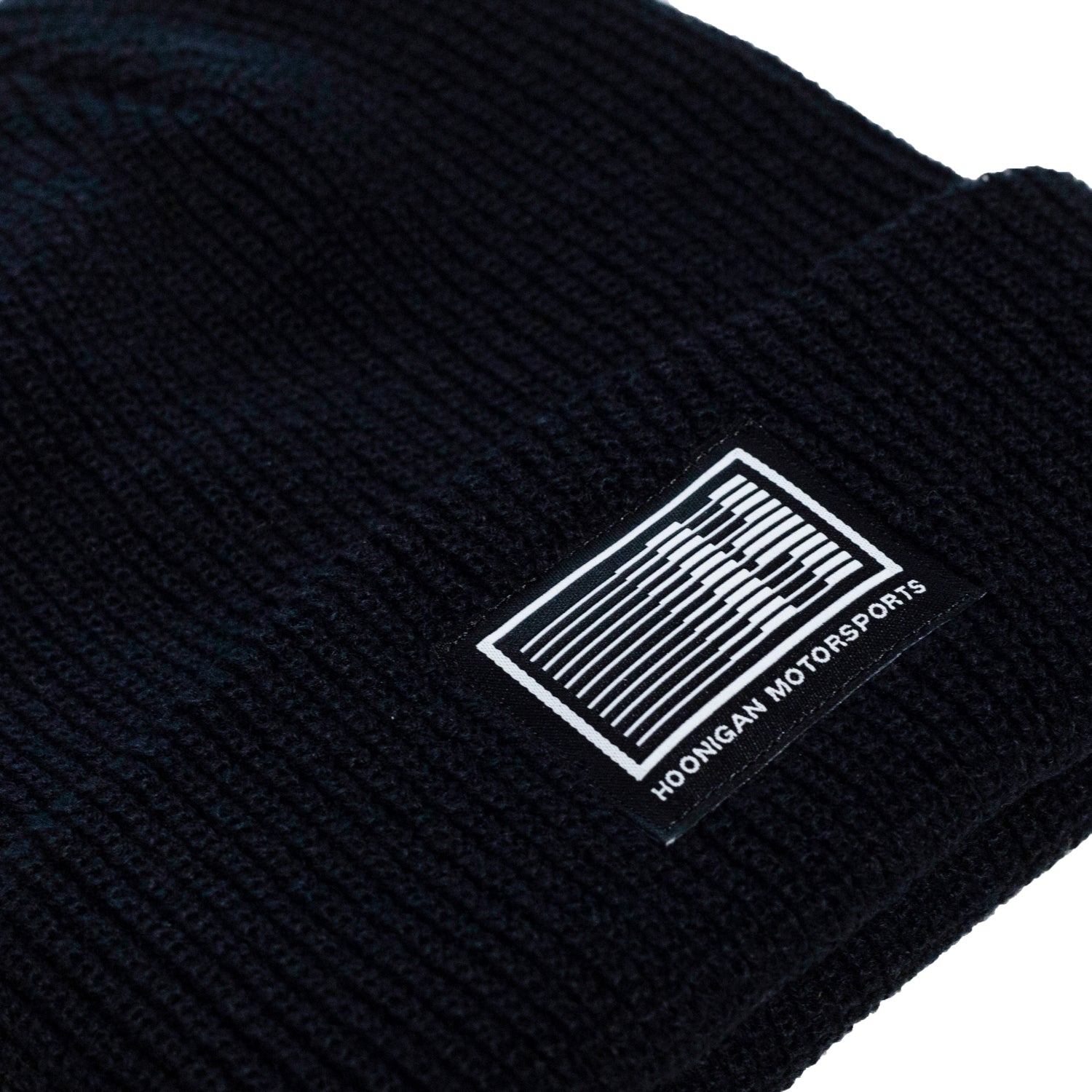 Black Hoonigan Motorsports beanie featuring a white logo on the front, ideal for motorsport enthusiasts.