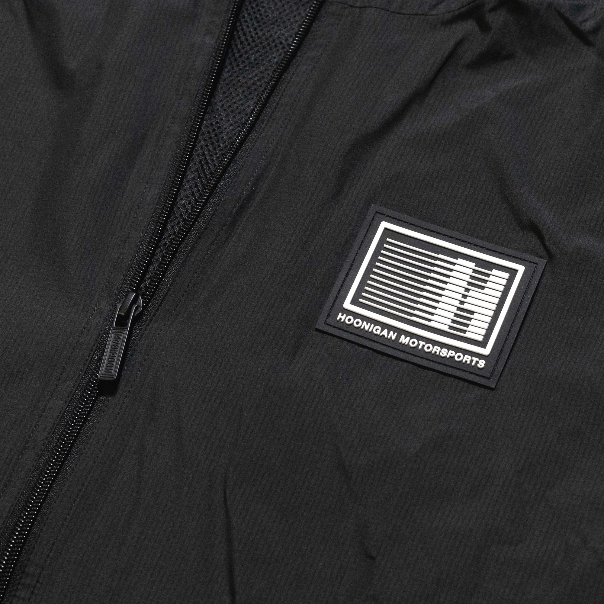 Hoonigan Motorsports windbreaker jacket featuring a bold front design in black and white.