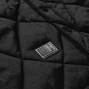 Hoonigan Motorsports VICTOR Quilted Jacket in black, featuring a zip closure, chest logo, and quilted design, displayed on a wooden background.