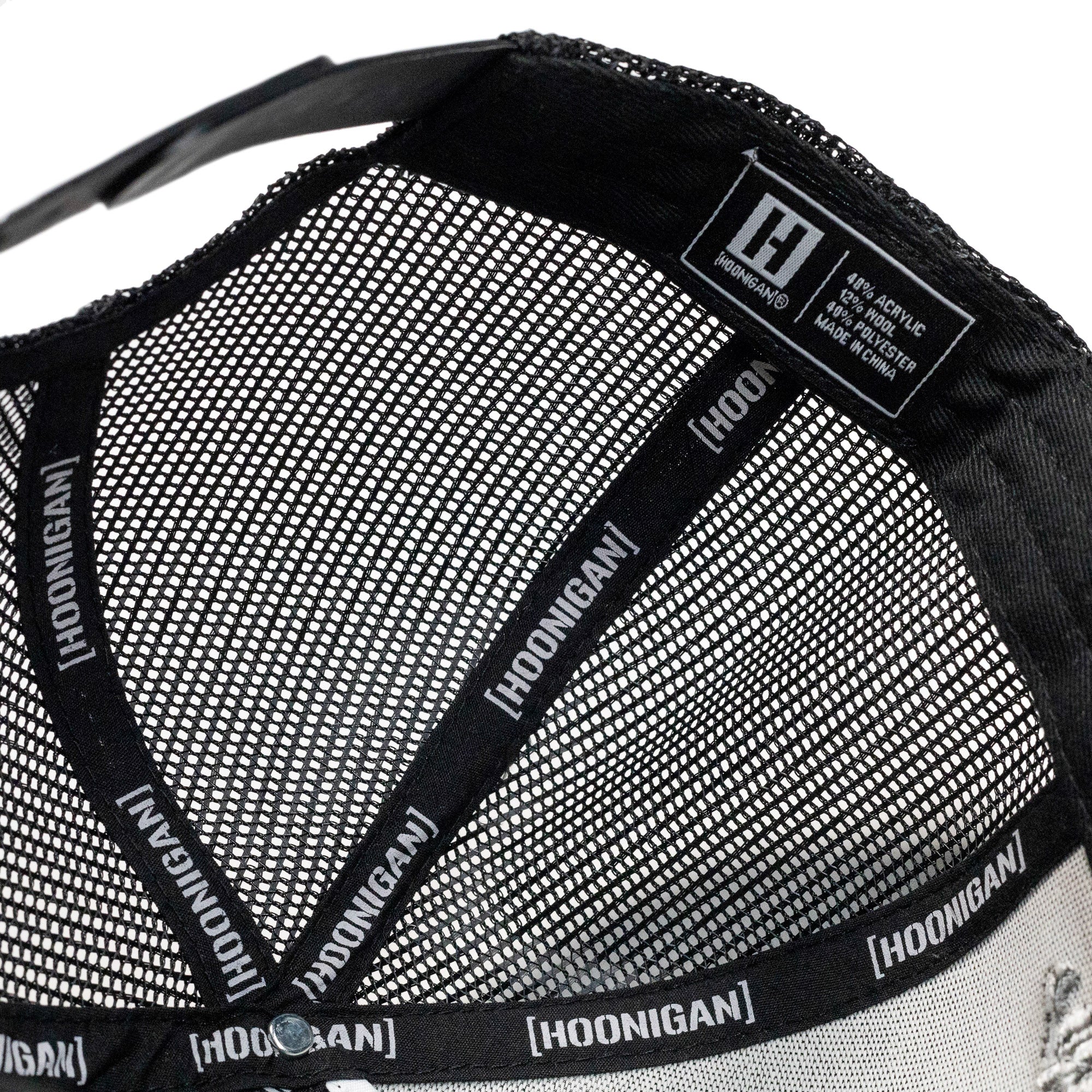 Close-up of the inside of a Hoonigan FIND OUT V2 snapback trucker hat, showing mesh lining, branded tape, and label details.