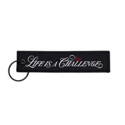 Hoonigan x Sayaka LIFE IS A CHALLENGE Jet Tag Keychain featuring bold graphics on a vibrant background.