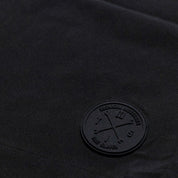 Close-up of Hoonigan Oil Slick board shorts featuring a black fabric and embossed logo patch for a stylish look.