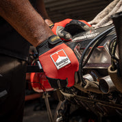 Hoonigan Surgeon General gloves worn by a mechanic working on a car engine in a garage setting.
