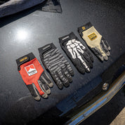Hoonigan FIND OUT Gloves displayed on a car hood, featuring various designs for motorsport enthusiasts.