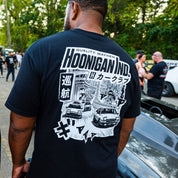 Back of the black Hoonigan 86 CREW tee: HOONIGAN IND. logo, Japanese text and street-scene car artwork in white.