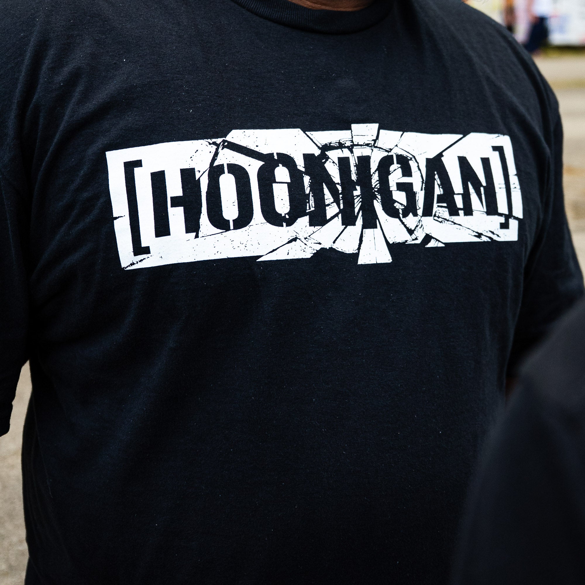Close-up of the shattered white [HOONIGAN] censor bar print on the black SHATTERED CENSOR BAR tee.