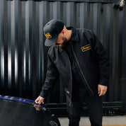 Hoonigan KNUCKLEBUSTERS jacket featuring a black classic design with the Hoonigan logo on the back and chest, ideal for motorsport enthusiasts.