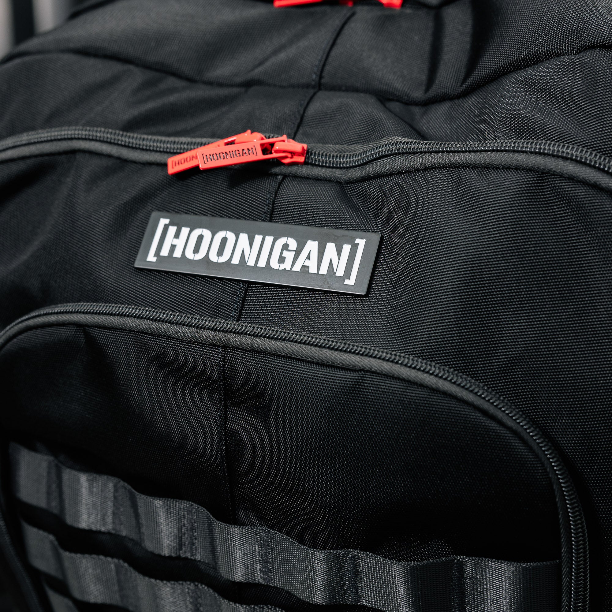 Hoonigan Ratchet Strap Backpack featuring a durable black exterior with vibrant neon accents and adjustable straps.