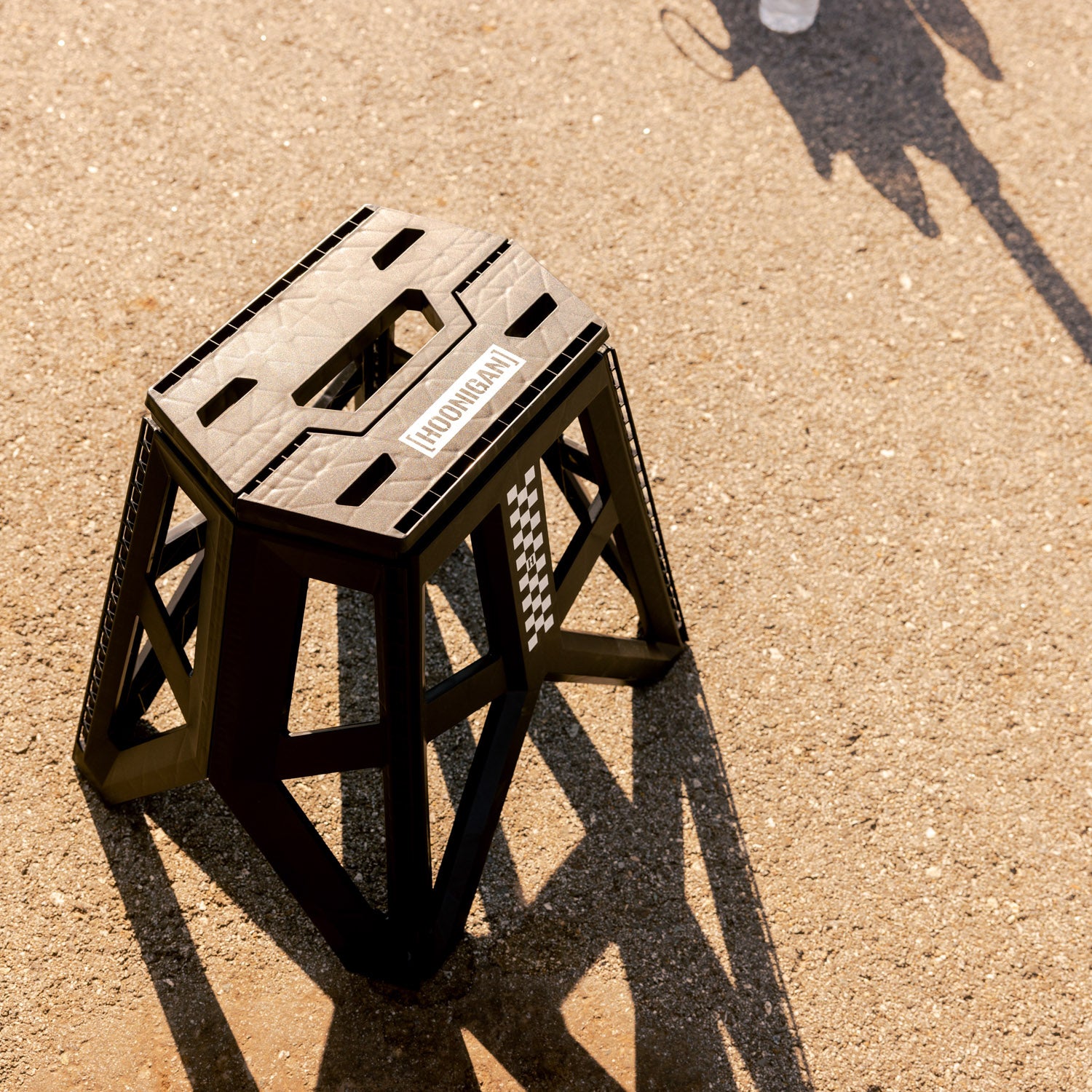 Hoonigan TRACK DAY collapsible stool with a black and white design, featuring the Hoonigan logo and a sturdy frame.