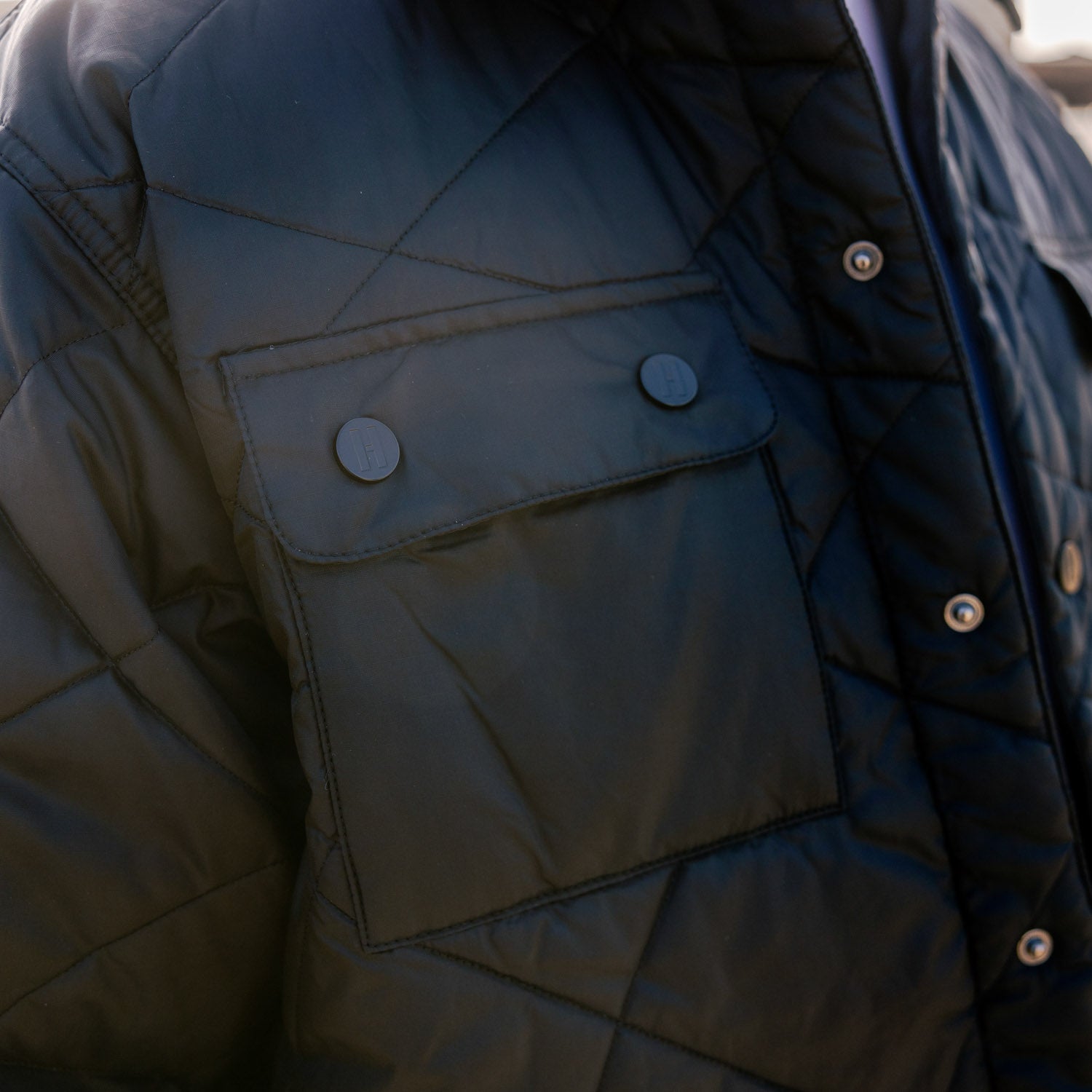 Hoonigan Motorsports VICTOR Quilted Jacket in black, featuring a zip-up front, ribbed cuffs, and Hoonigan logo on the chest.