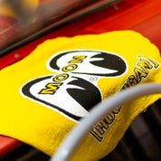 Hoonigan X Mooneyes shop towel featuring a bold yellow design with the iconic HOON and MOON logos. Perfect for automotive enthusiasts.