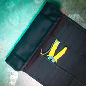 Hoonigan LIL TOOL ROLL opened on a concrete surface, featuring yellow tools and a compact storage design.