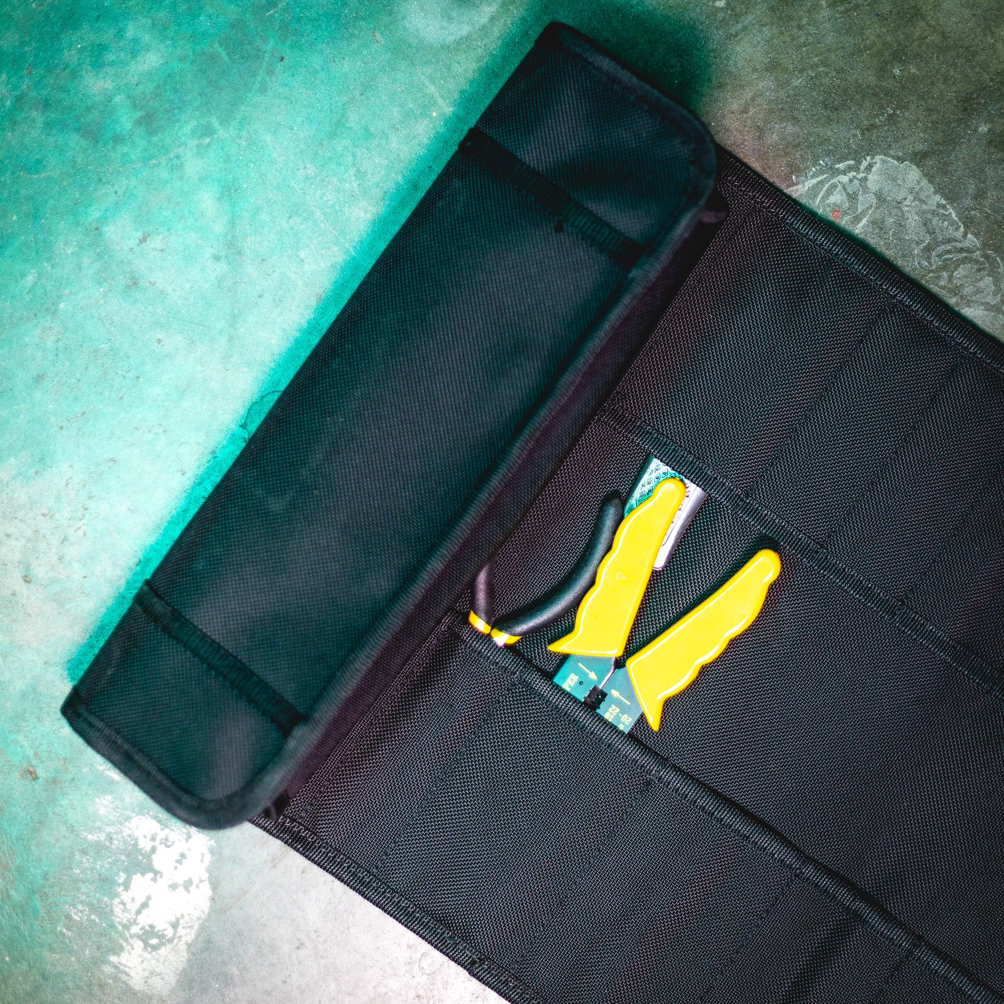 Hoonigan LIL TOOL ROLL opened on a concrete surface, featuring yellow tools and a compact storage design.