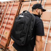 Hoonigan METAL BAR Backpack in black with logo detail, featuring adjustable straps and a front zip pocket.