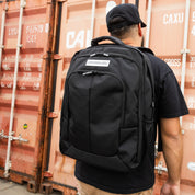 Hoonigan METAL BAR Backpack featuring a sleek black design with a prominent logo, adjustable straps, and multiple compartments for storage.