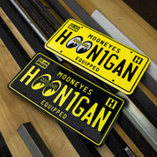 Hoonigan x Mooneyes EQUIPPED license plates in vibrant yellow and black, showcasing bold branding for car enthusiasts.