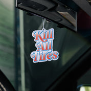Hoonigan KILL ALL TIRES V2 air freshener featuring a vibrant graphic design and bold typography on a circular shape, hanging from a string.