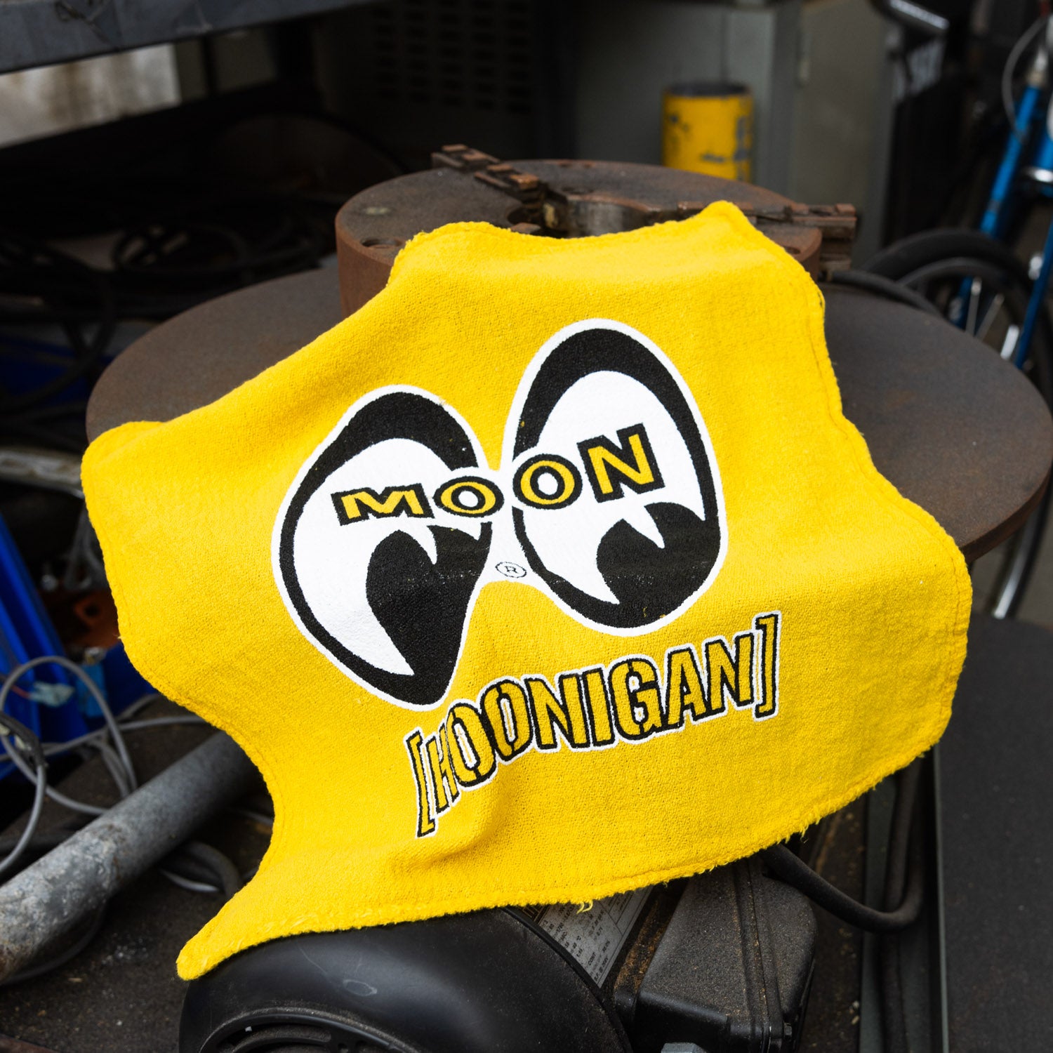 Bright yellow shop towel featuring the Hoonigan and Mooneyes logos, perfect for automotive enthusiasts and garage use.