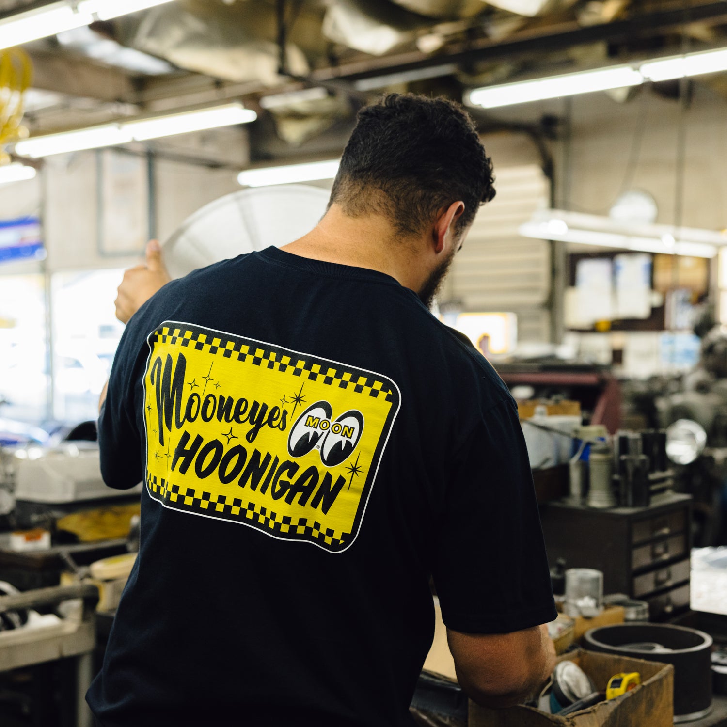 "Black short sleeve tee featuring Hoonigan x Mooneyes logo and 'GO WITH HOON' text, displayed on a flat surface."