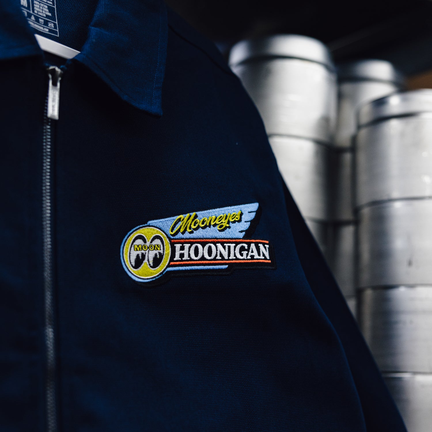 Hoonigan x Mooneyes MOON MOTEL Jacket featuring a black exterior, colorful embroidered logos, and retro motel design elements.