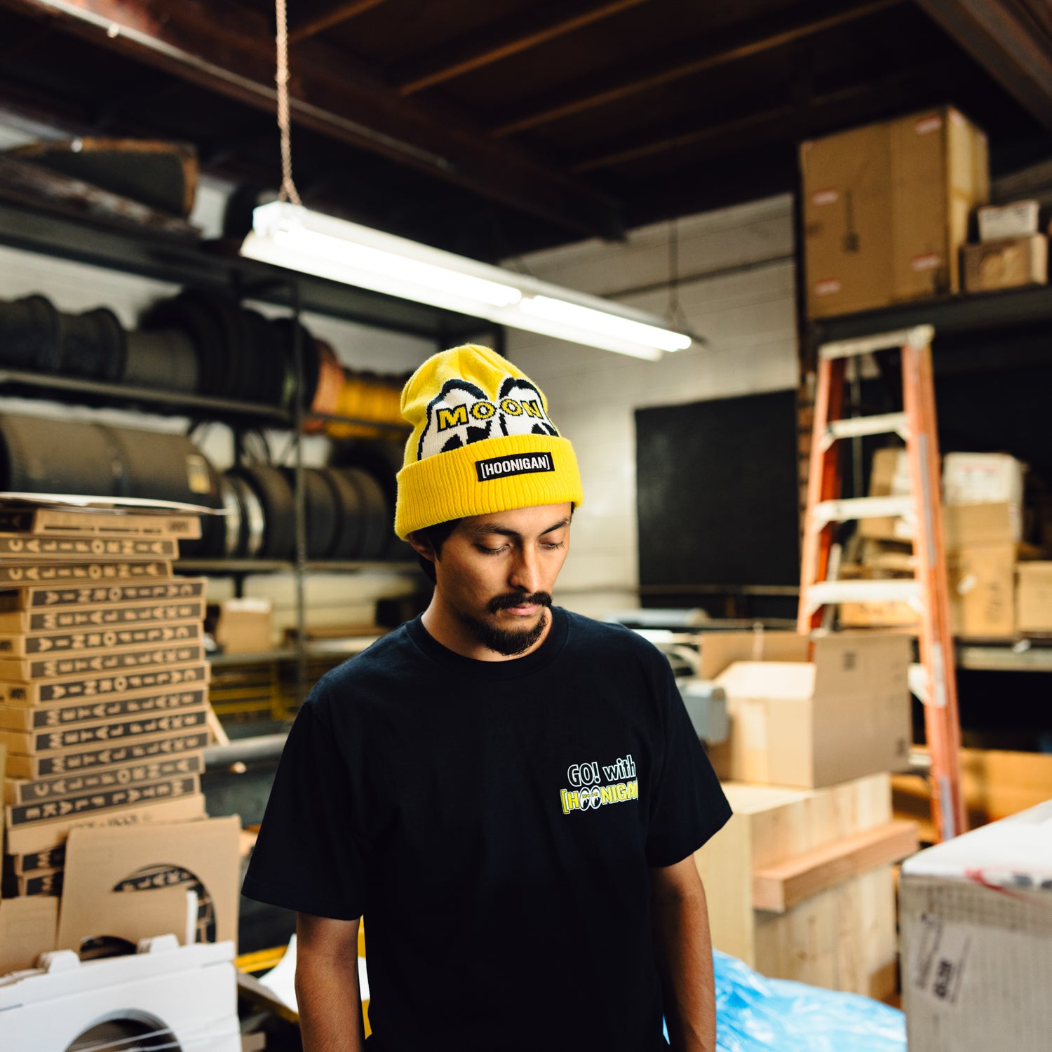 Hoonigan x Mooneyes LQQK Beanie featuring a black knit design with contrasting yellow and white logos.