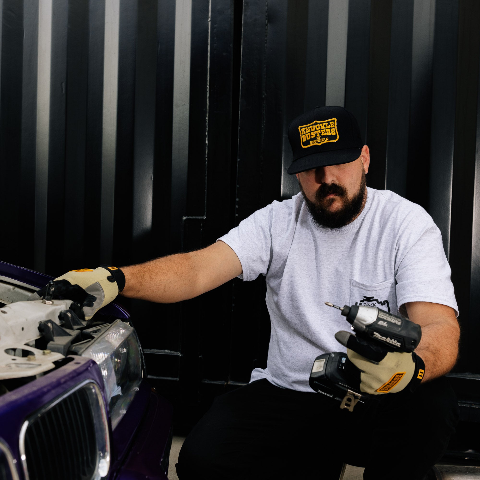 Hoonigan Belt Sander Snapback Hat featuring a black and yellow design with a graphic of a belt sander and embroidered logo on the front.