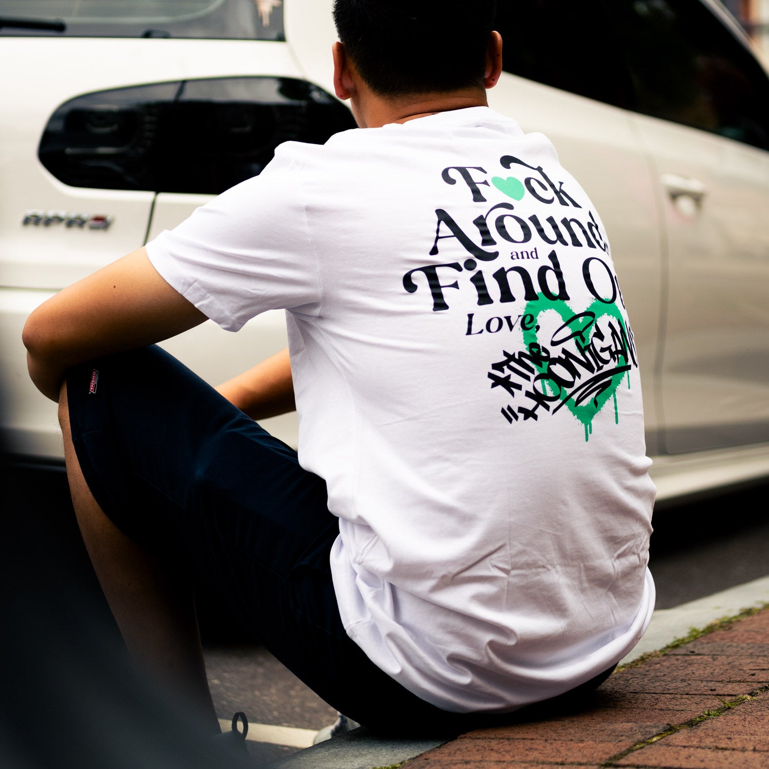 Black short sleeve tee featuring the bold "FIND OUT 2.0" graphic and Hoonigan logo on the front, perfect for motorsport enthusiasts.