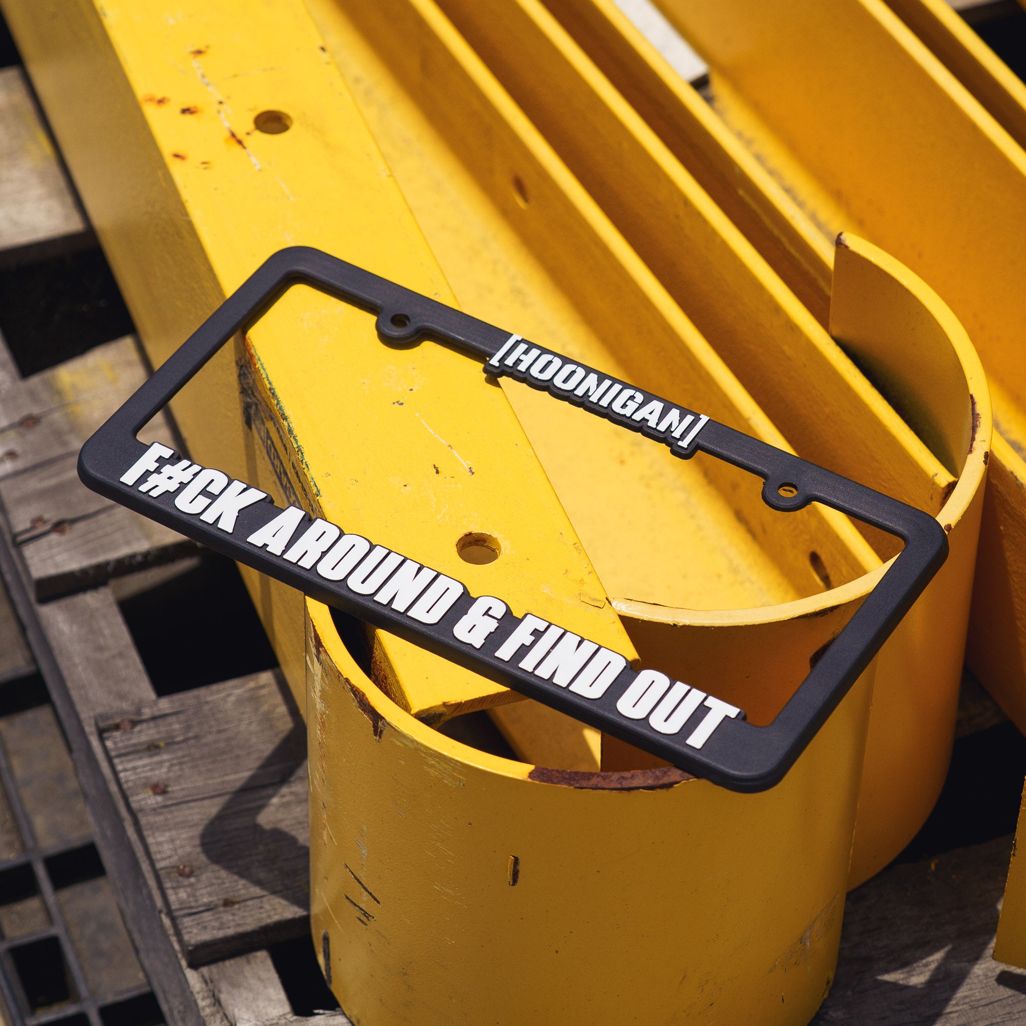 Black license plate frame with white text that reads "HOONIGAN" and "FCK AROUND & FIND OUT" 