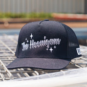 Black snapback trucker hat with "The Hoonigans" embroidered in white, featuring star accents and mesh back panels.