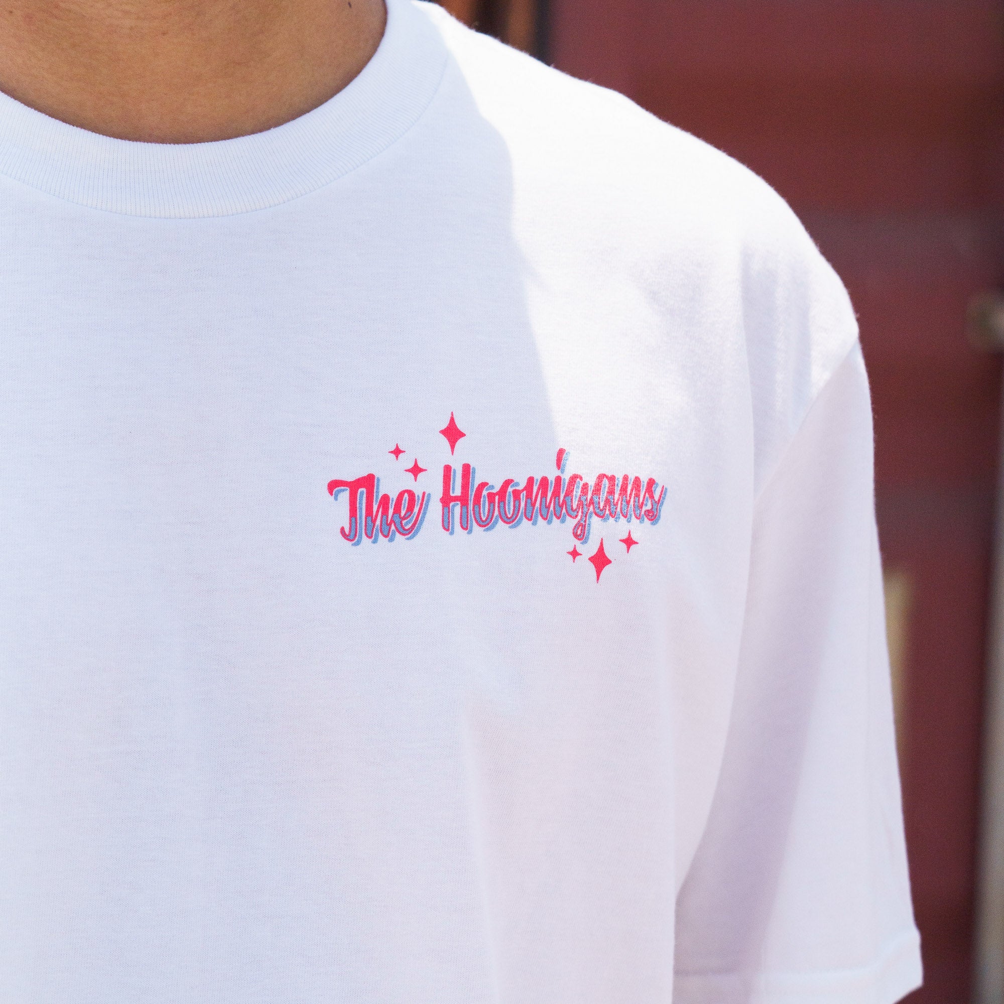 White Hoonigan FIND OUT V2 short sleeve tee with pink and blue logo and star accents on the chest.