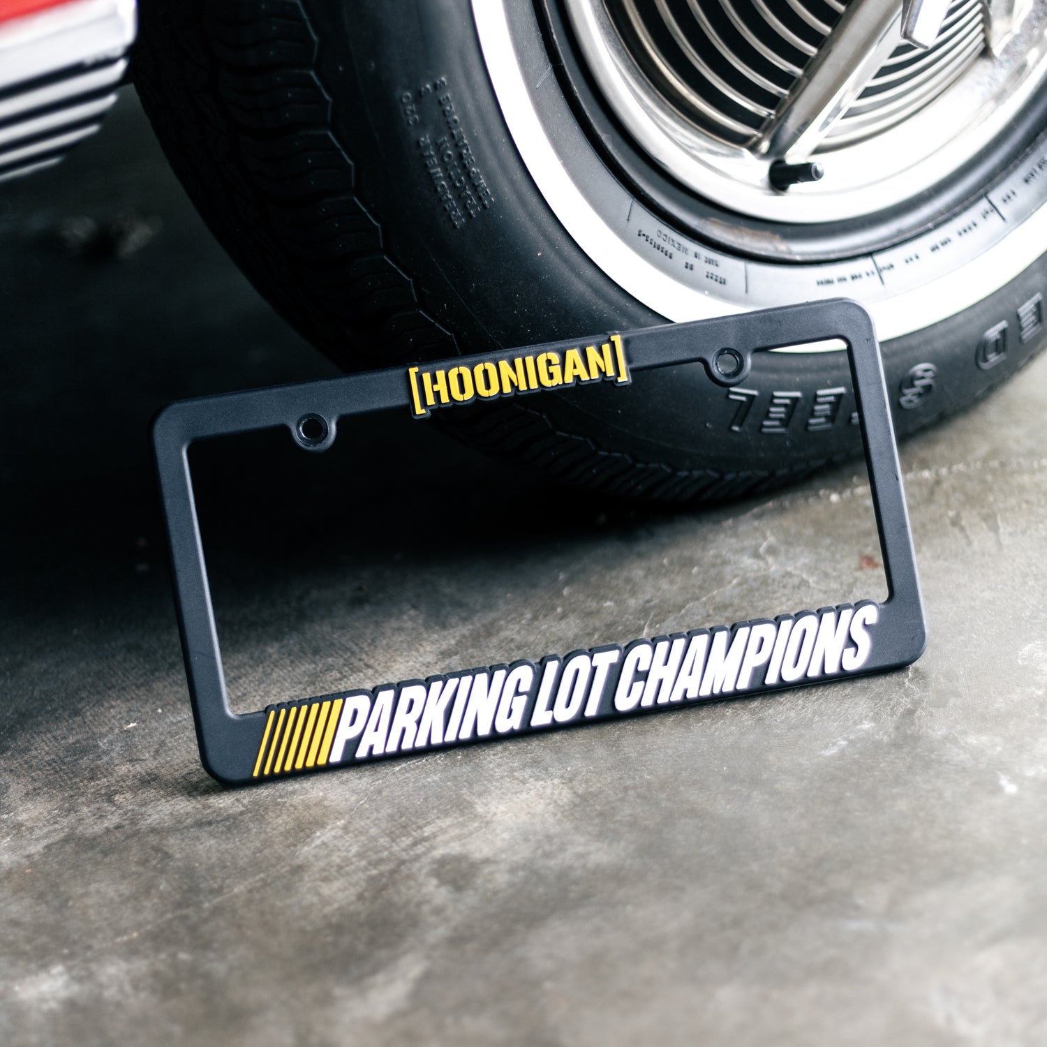 Hoonigan PARKING LOT CHAMPIONS license plate frame with bold graphic design and durable material, ideal for car enthusiasts.