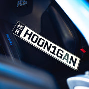 Hoonigan EURO license plate displayed on a car seat, showcasing bold lettering and racing-inspired design.